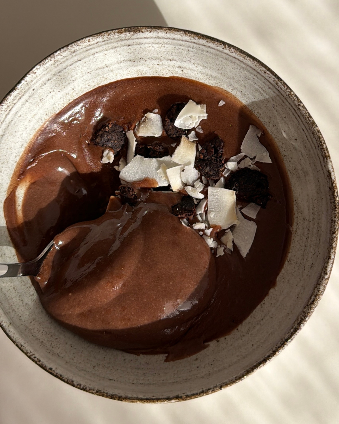 Skål med proteinrik och enkel chokladmousse med 29 g protein som är toppad med mörk choklad och kokosflakes