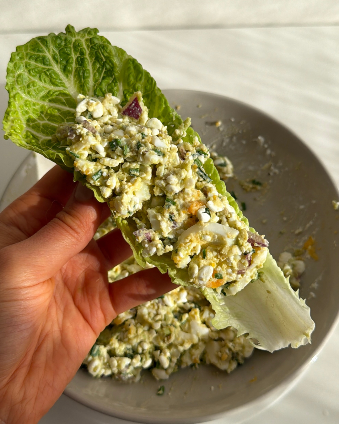 Hand som håller i ett salladsblad fylld med en krämig äggröra med 26g protein 