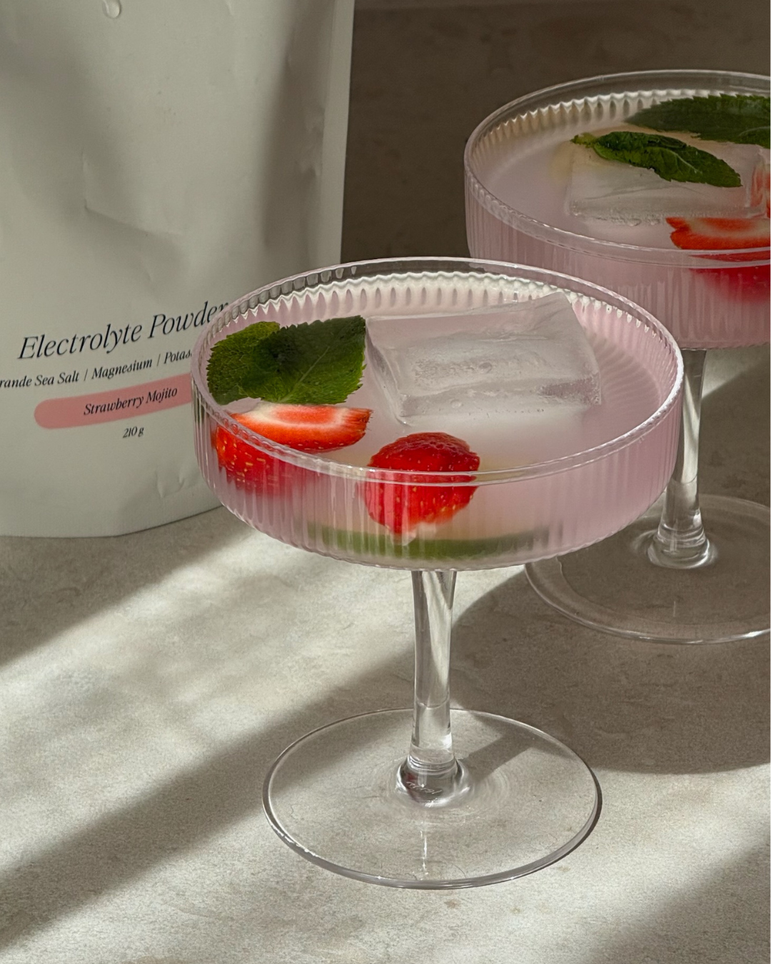 Cocktailglas med en rosa alkoholfri strawberry mojito mocktail utan socker med elektrolyter