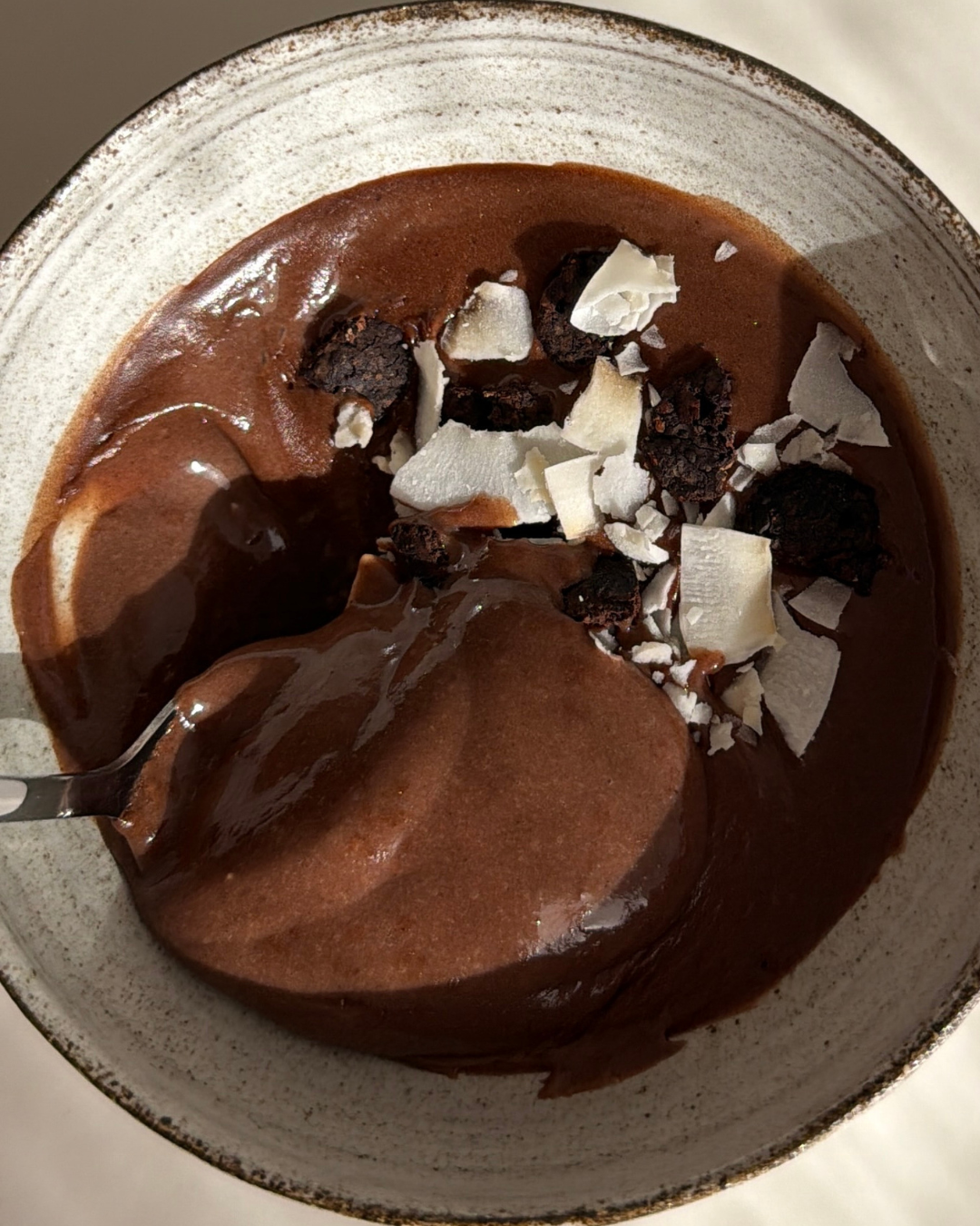 Skål med proteinrik och enkel chokladmousse med 29 g protein som är toppad med mörk choklad och kokosflakes