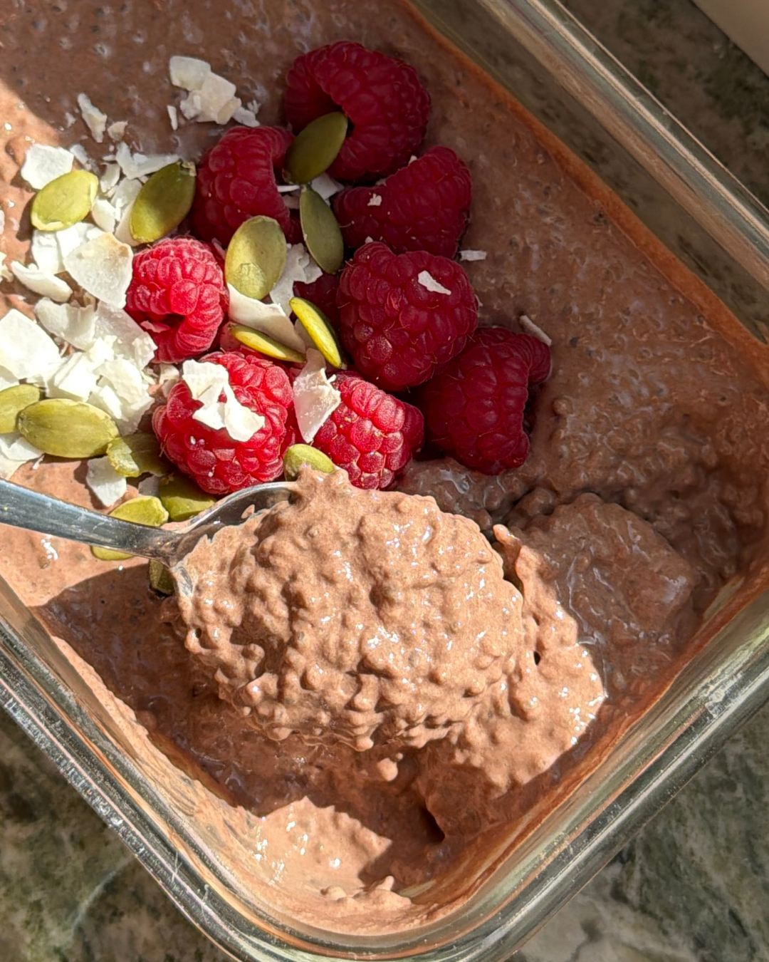 Krämig chiapudding med kako som är toppad med hallon, pumpafrön och kokosflakes. En proteinrik chiapudding med Womensync osötat vaniljprotein som smakar som chokladmousse