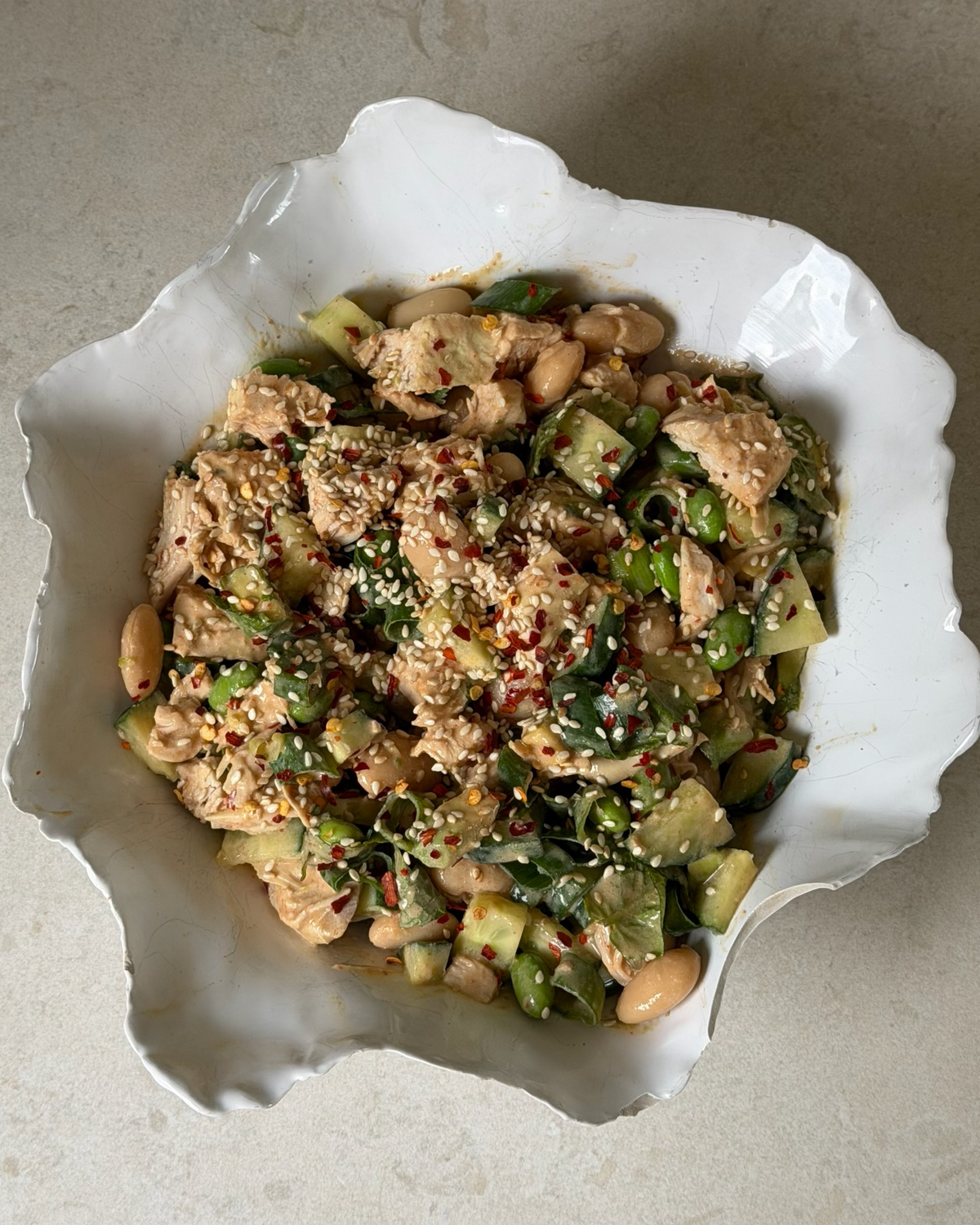 Vit skål med krämig kyckling satay sallad med 50 g protein gjord på kyckling, vita bönor, jordnötssmör och färsk mynta